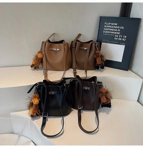 Litchi pattern leather bucket bags with metal twist locks and camel plush charms