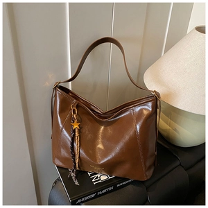Détail d'un sac cabas vintage marron avec bijou étoile et pompon sur livre noir