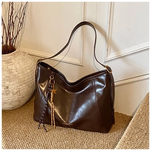 Détail du sac cabas en cuir brillant marron café avec breloque étoile et pompon