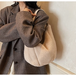 Close-up of fluffy beige faux fur shoulder bag with leather strap and soft texture