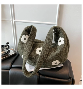 Gros plan du sac en tricot vert foncé avec motif de fleurs blanches sur siège en cuir
