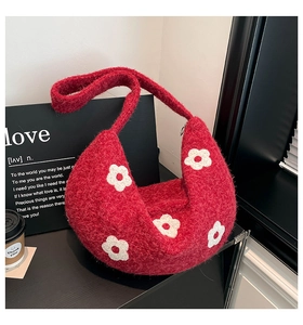 Gros plan du sac sous le bras en peluche rouge avec texture tricotée et motifs de fleurs