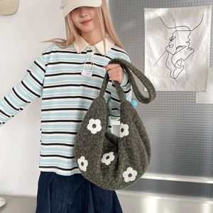 Détail du sac à bandoulière en tricot vert avec motifs de fleurs blanches en peluche