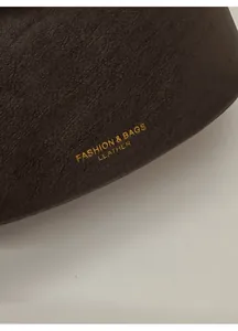 Detailed close-up of dark brown leather texture with elegant gold embossed fashion lettering