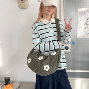Détail de la texture d'un sac bandoulière en tricot vert mousse avec broderies marguerites