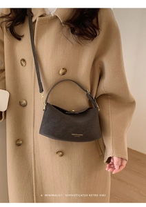 Detail of dark brown leather handbag styled with a camel coat for a retro minimalist vibe