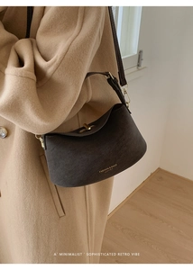 Detail of premium brown suede bucket bag with gold metal twist lock and leather branding
