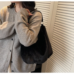 Detail of black faux fur shoulder bag with leather strap and golden metal hardware