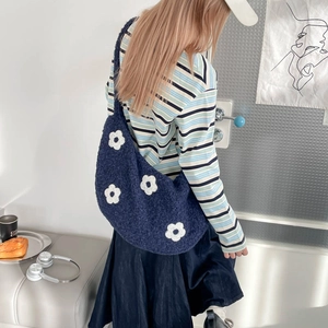 Texture détaillée du sac peluche bleu avec motifs fleurs blanches sur tissu laine d'agneau