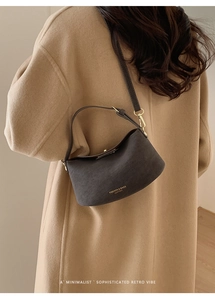 Close-up of a minimalist half-moon crossbody bucket bag in dark brown textured leather