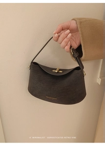 Close-up of a vintage coffee brown leather handbag featuring a stylish metal twist lock