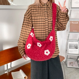 Détail du sac hobo en crochet rouge avec motifs de fleurs 3D et large bandoulière en maille