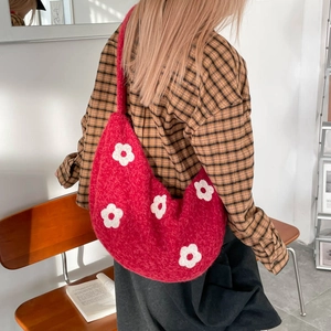 Détail du sac croissant en tricot rouge avec motifs floraux blancs et texture douce