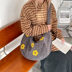 Détail de la texture tricotée en peluche grise et du motif floral jaune du sac hobo