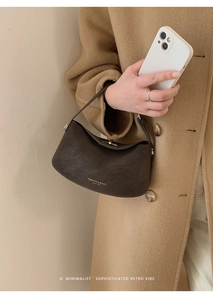 Detail of dark brown leather handbag with gold metal clasp and textured finish