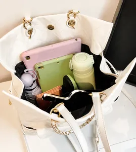 Interno spazioso della borsa tote trapuntata crema con tablet e oggetti quotidiani