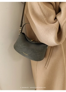 Detail of dark grey leather handbag with gold twist lock and logo on wool coat