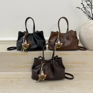 Trois sacs seaux en noir, caramel et marron avec breloques d'ours sur marches en pierre