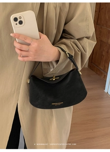 Close-up of black leather bucket bag with gold logo text and metal clasp closure