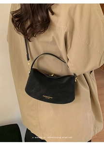 Detail view of a black vintage leather bucket bag styled with a khaki trench coat