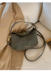 Detailed view of dark olive leather bucket bag with gold clasp and adjustable strap