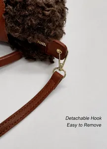 Detail of detachable gold metal clasp and brown lychee leather strap on fluffy bag