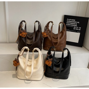Detailed close-up of large hobo tote bags in brown, white, and black with bear charms