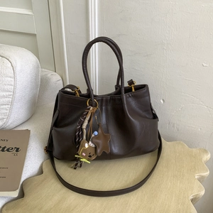Détail du sac à main en cuir marron foncé avec charm ours et bandoulière réglable