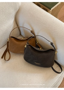 Detail view of retro leather bucket bags in brown and grey on a textured sofa
