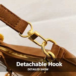 Macro detail of the golden swivel hook and D-ring on the brown leather crossbody bag