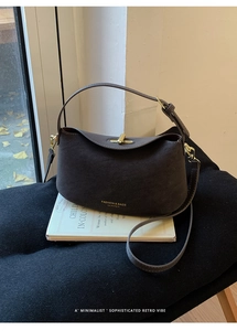 Detail of vintage brown suede crossbody bag with gold twist lock on classic books