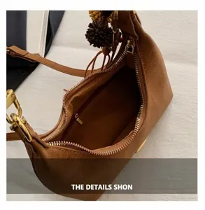 Detail view showing interior zipper pocket and gold hardware of the brown suede handbag