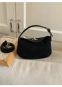 Detail of black suede hobo bag with gold twist-lock and detachable strap in a cozy setting