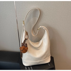 Detail of off-white faux leather tote bag with zip closure and cute brown teddy bear charm