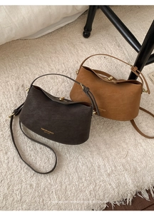 Detail of coffee and caramel leather bucket bags showing gold text and metal clasp