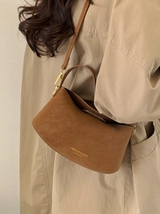 Brown minimalist suede bucket bag for women with gold lettering and adjustable shoulder strap