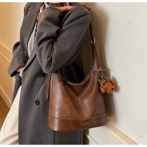 Detail of brown PU leather tote bag with decorative stitching and leopard bow bear charm