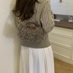 Graue Teddy-Plüschtasche mit braunem Lederriemen am Modell in häuslicher Umgebung