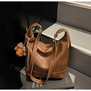 Detailed close-up of brown matte leather Hobo tote bag with teddy bear and tassel pendant