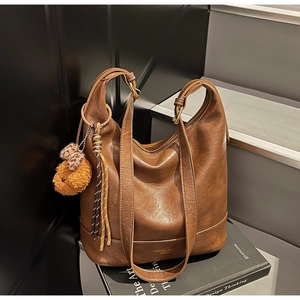 Detail of vintage brown leather tote bag with gold lettering and plush bear charm