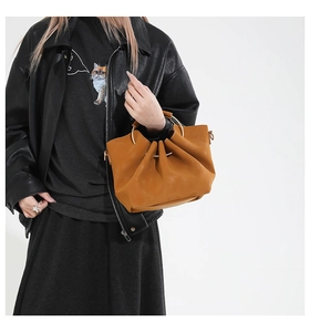 Détail du sac seau marron en PU avec design plissé et poignées anneaux dorées chic