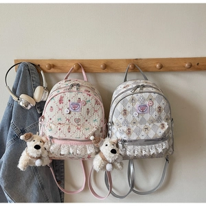 Détail de sacs à dos à fleurs matelassés avec bordure en dentelle et pendentif chien