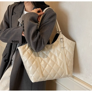 Dettaglio della borsa tote trapuntata beige con finitura lucida e fibbia in metallo
