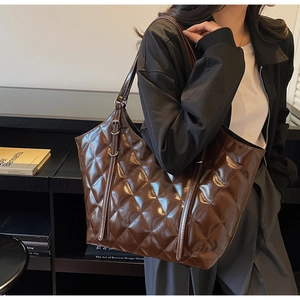 Dettaglio ravvicinato della borsa tote trapuntata marrone con finitura lucida e fibbia del cinturino