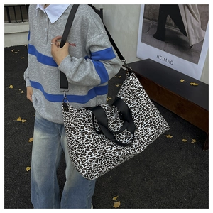 Dettaglio della grande borsa tote leopardata con tracolla in tessuto nero sul modello
