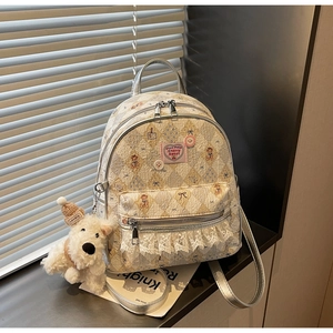Détail du sac à dos ivoire avec motifs d'ours et de fleurs, et son porte-clés chien en peluche