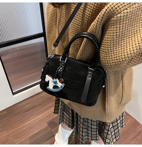 Detail of matte black Boston bag with MUHETI SHI SHANG embossing and horse charm