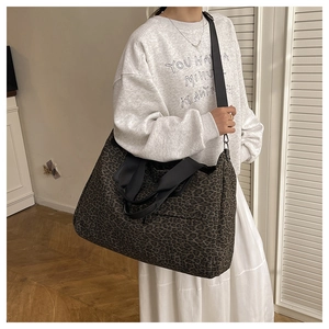 Dettaglio di una borsa tote leopardata con tracolle nere indossata da una modella in casual