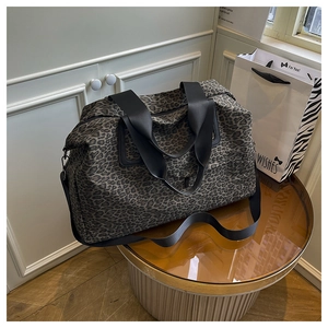 Dettaglio della borsa da viaggio leopardata con robuste cinghie nere e zip in metallo