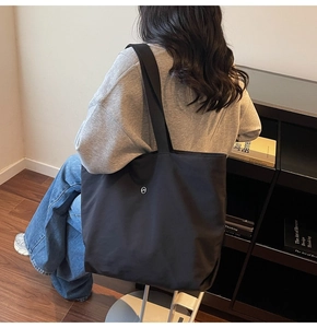 Vista detallada de un bolso tote negro de gran capacidad llevado al hombro por modelo